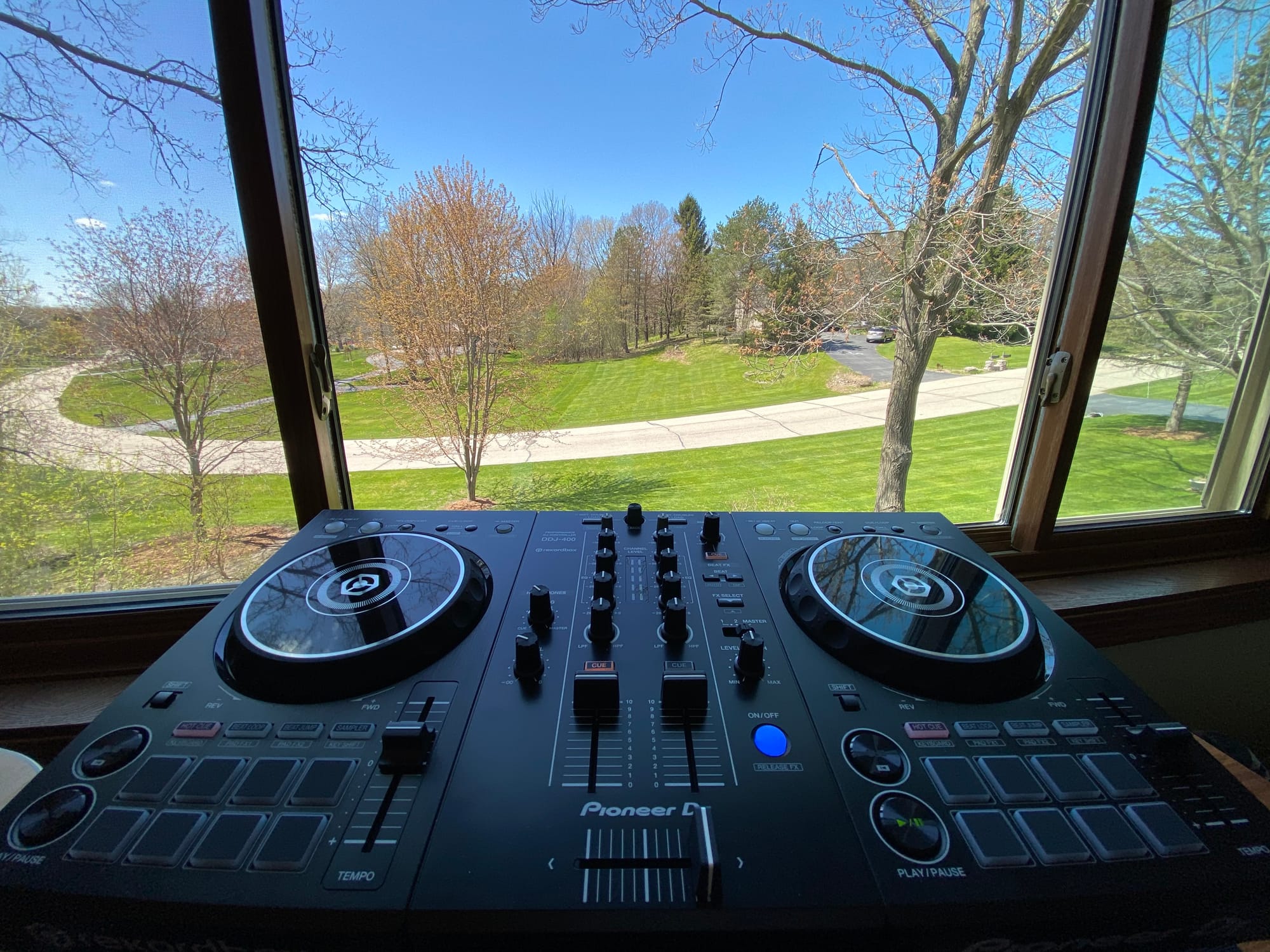 Photograph of a Pioneer DJ deck against the backdrop of my front yard through my office window