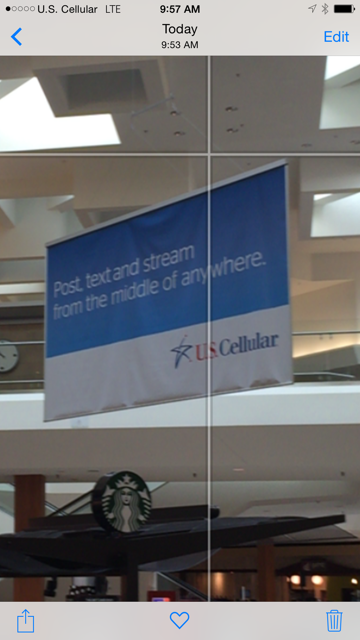 US Cellular banner hanging inside of a mall with overlaid iOS interface showing a poor signal and US Cellular carrier name