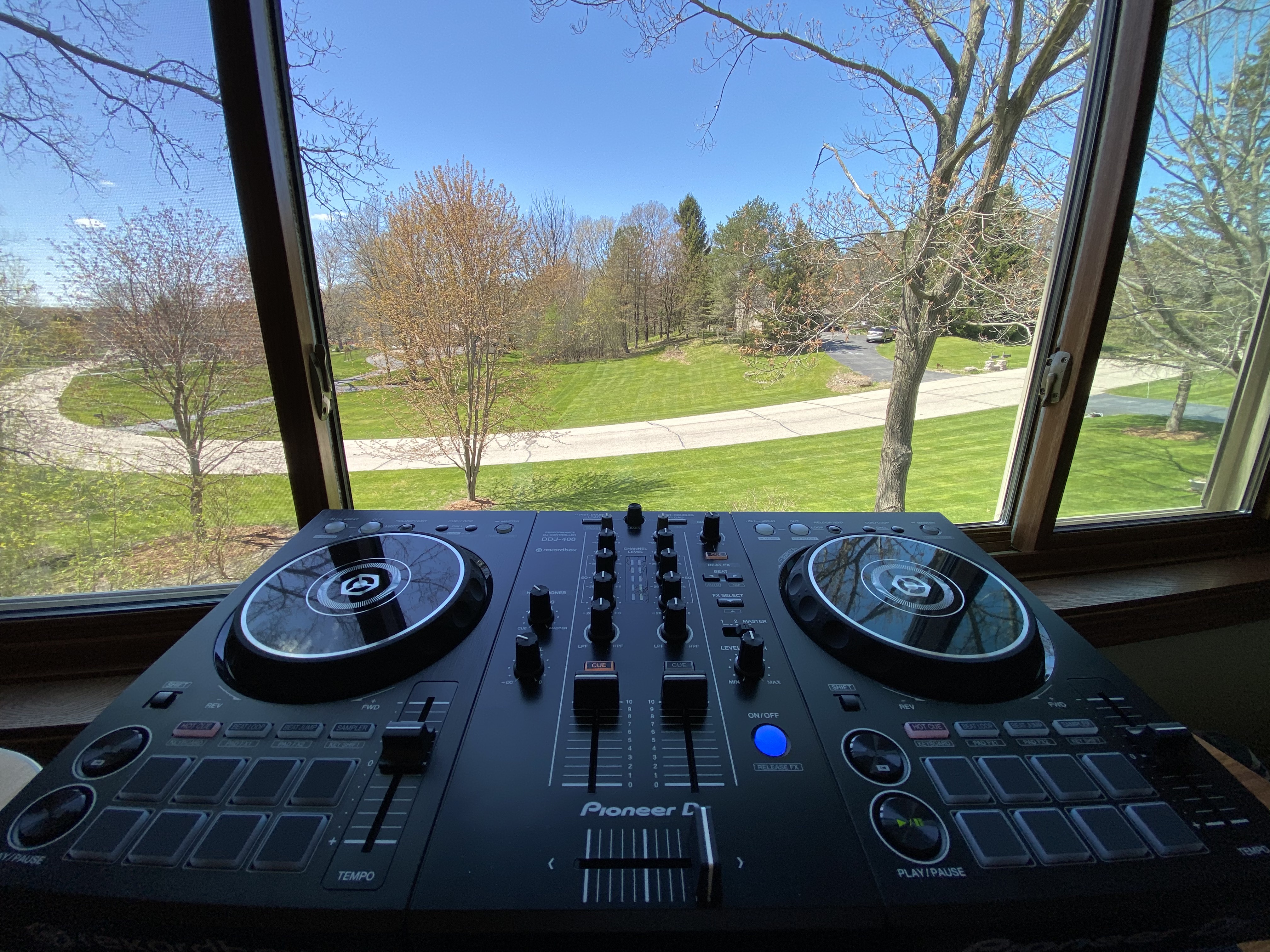 Photograph of a Pioneer DJ deck against the backdrop of my front yard through my office window